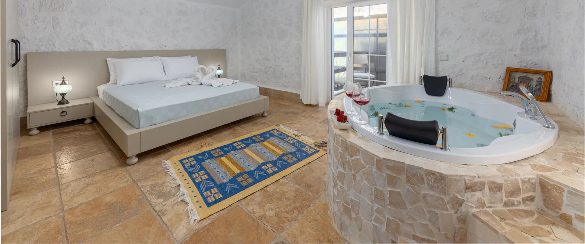 Illustrative hotel suite with a whirlpool tub beside the bed