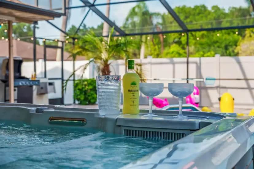 a swimming pool with glasses and a bottle of wine