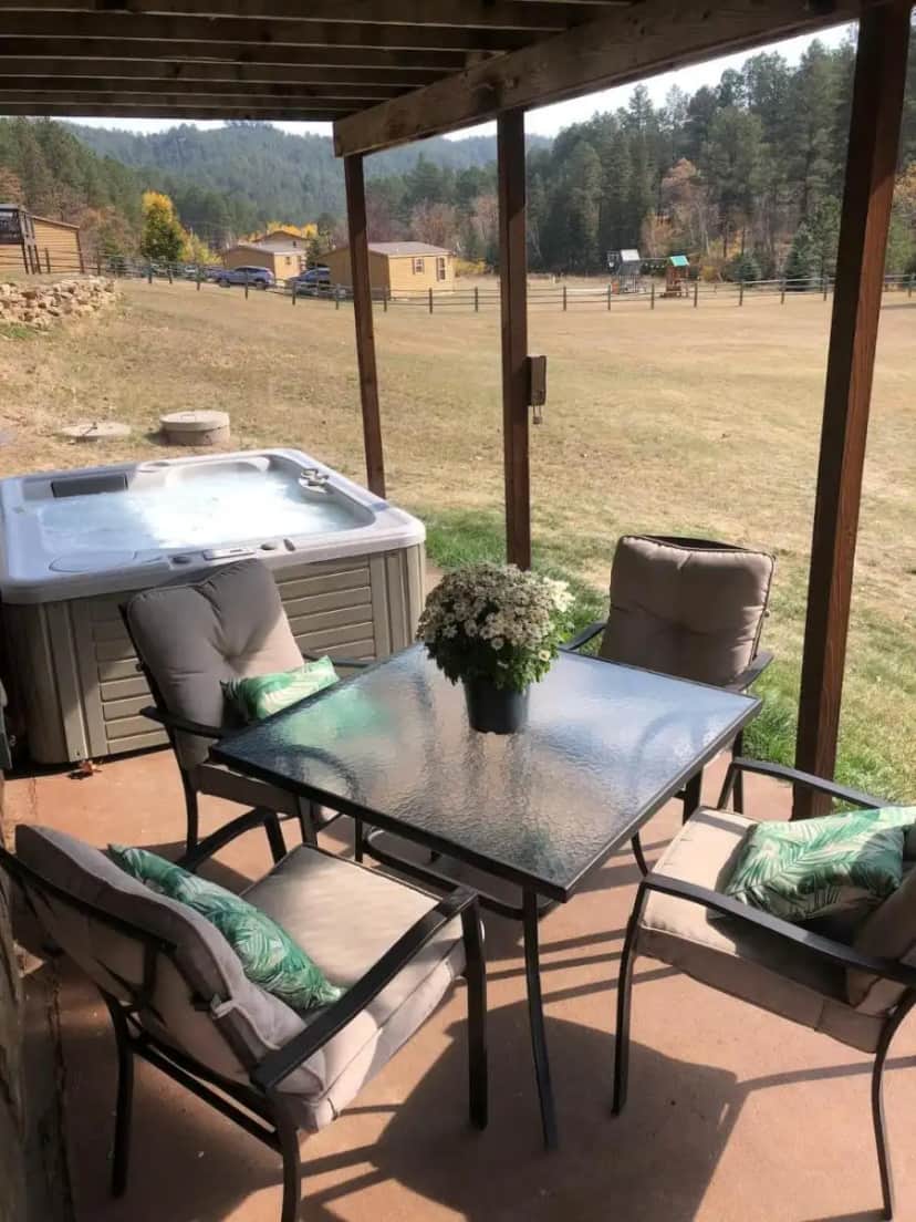 a table and chairs on a patio with a hot tub at 5 Miles from Mt- Rushmore with private hot tub in Keystone