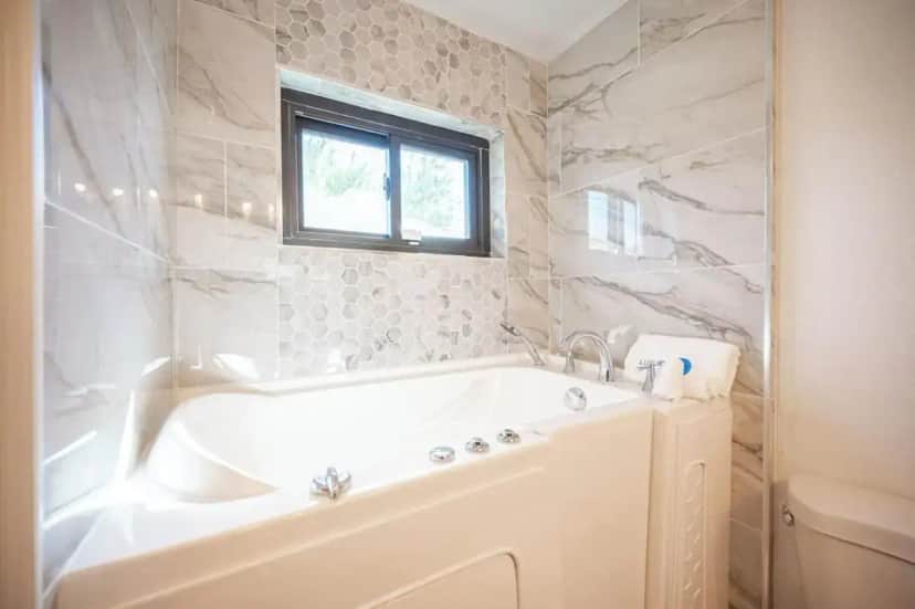 a white bathroom with a tub and a window at A Slice of Paradise in Sin City in Las Vegas