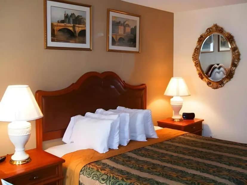 a bedroom with a bed with white pillows and two lamps at A VICTORY HOTEL - SOUTHFIELD in Southfield