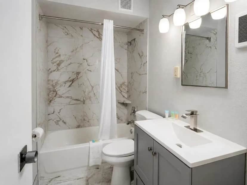 a white bathroom with a toilet and a sink at Alamo Inn & Suites in Gillette