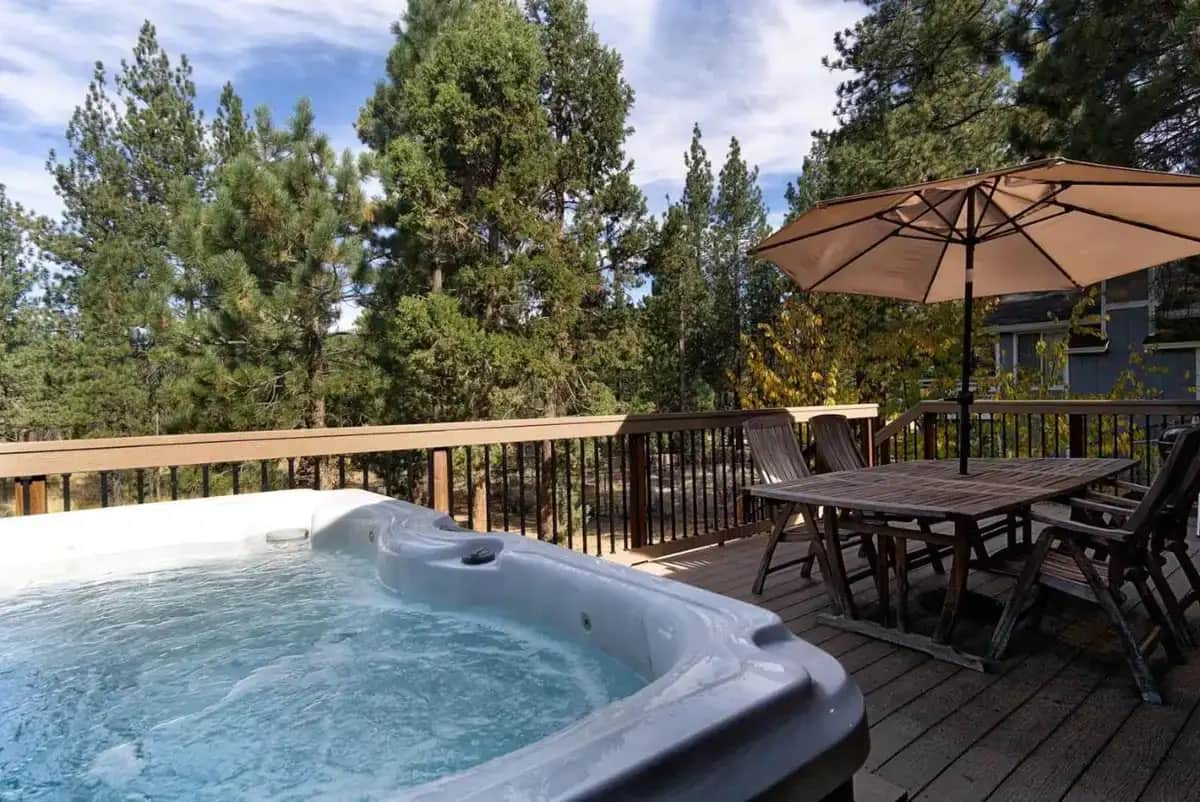 a hot tub on a deck with a table and an umbrella at All About Fun-1149 by Big Bear Vacations in Big Bear Lake