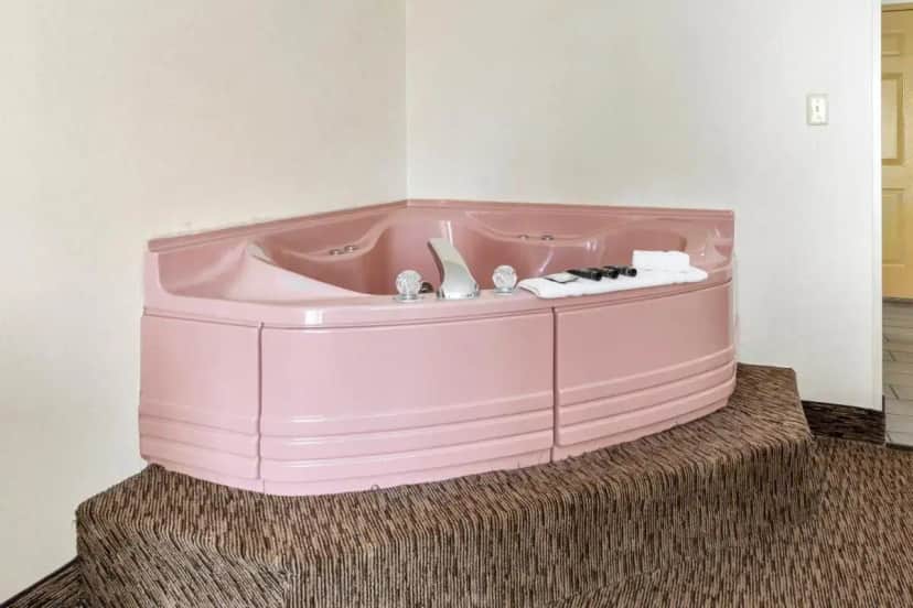a pink bath tub sitting on a rug in a room at Americana Hotel Boardwalk in Ocean City