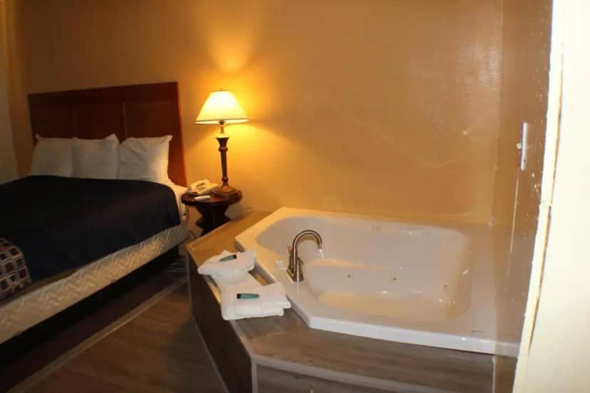 a hotel room with a tub and a bed at Americas Best Value Inn Geneva in Geneva