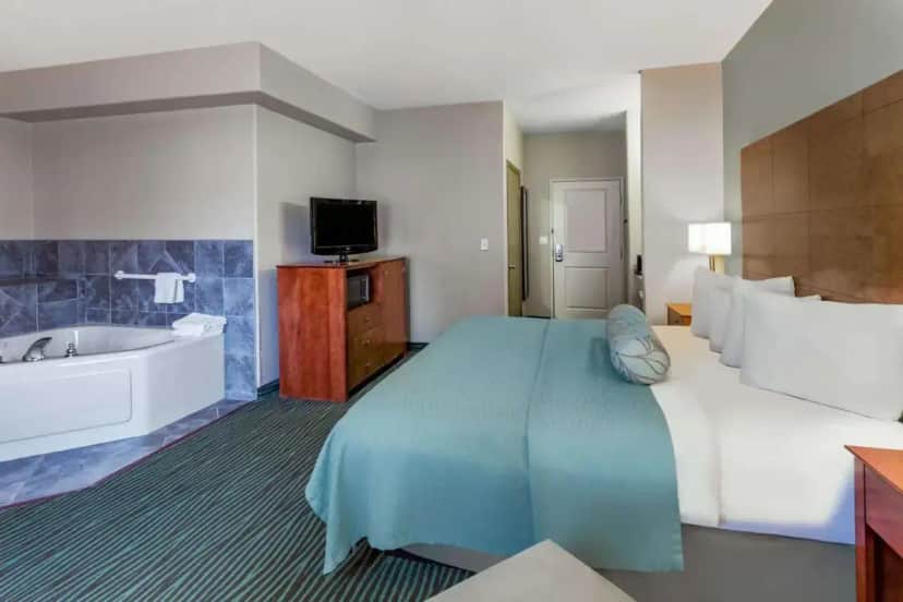 a hotel room with a large bed and a tub at AmericInn by Wyndham Des Moines Airport in Des Moines