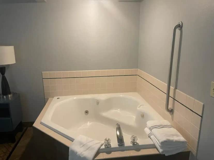 a bathroom with a bath tub with towels in it at AmericInn by Wyndham Hartford WI in Hartford