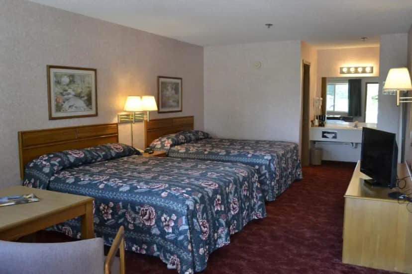 a hotel room with two beds and a television at Apple Blossom Inn in Eureka Springs