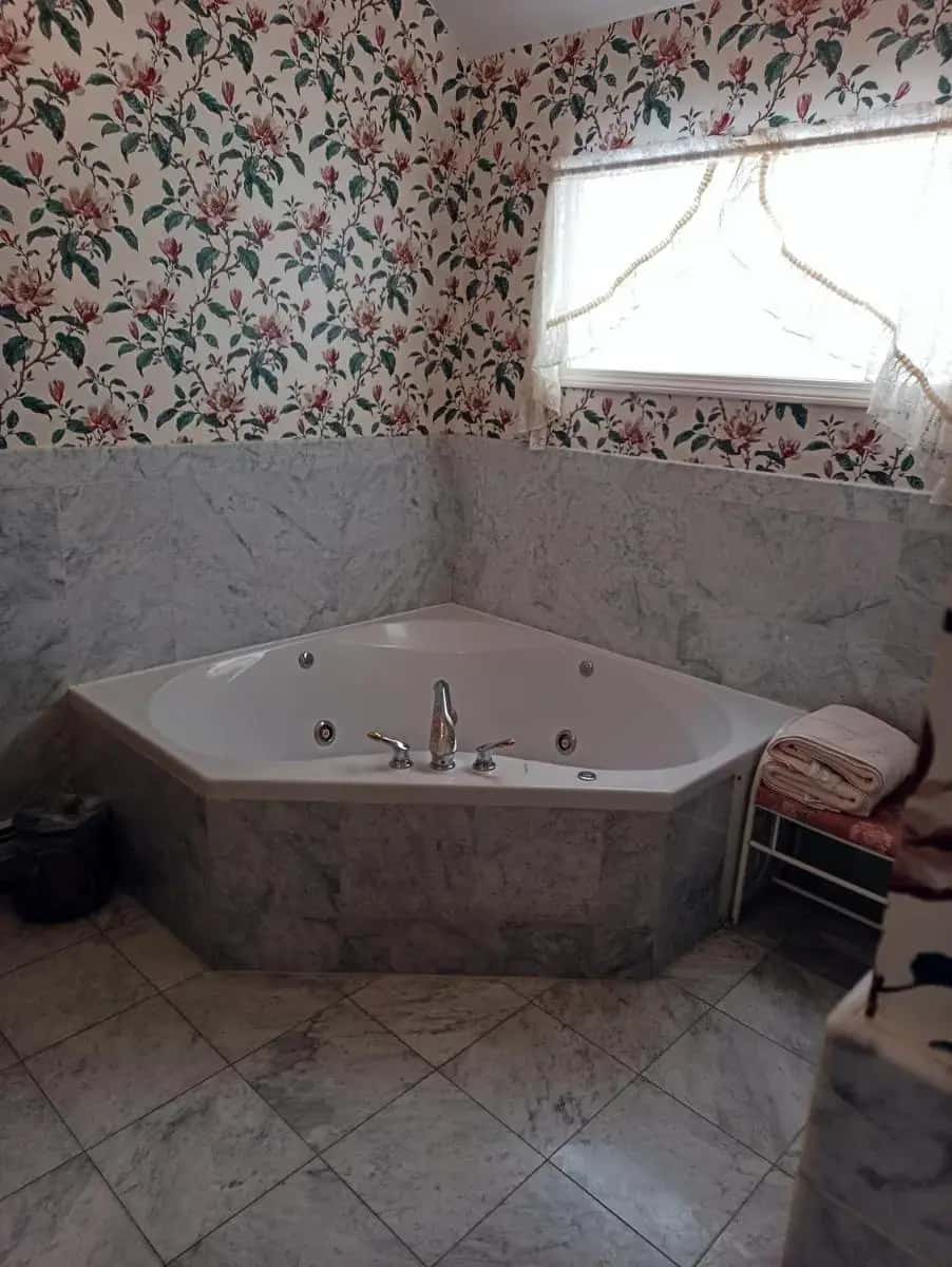 a bath tub in a bathroom with floral wallpaper at Arlington Inn & Spa in Arlington