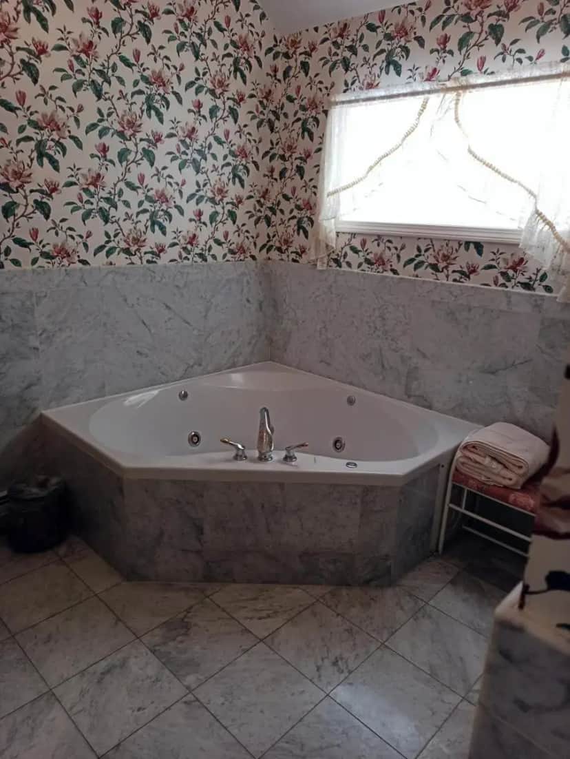 a bath tub in a bathroom with floral wallpaper at Arlington Inn & Spa in Arlington