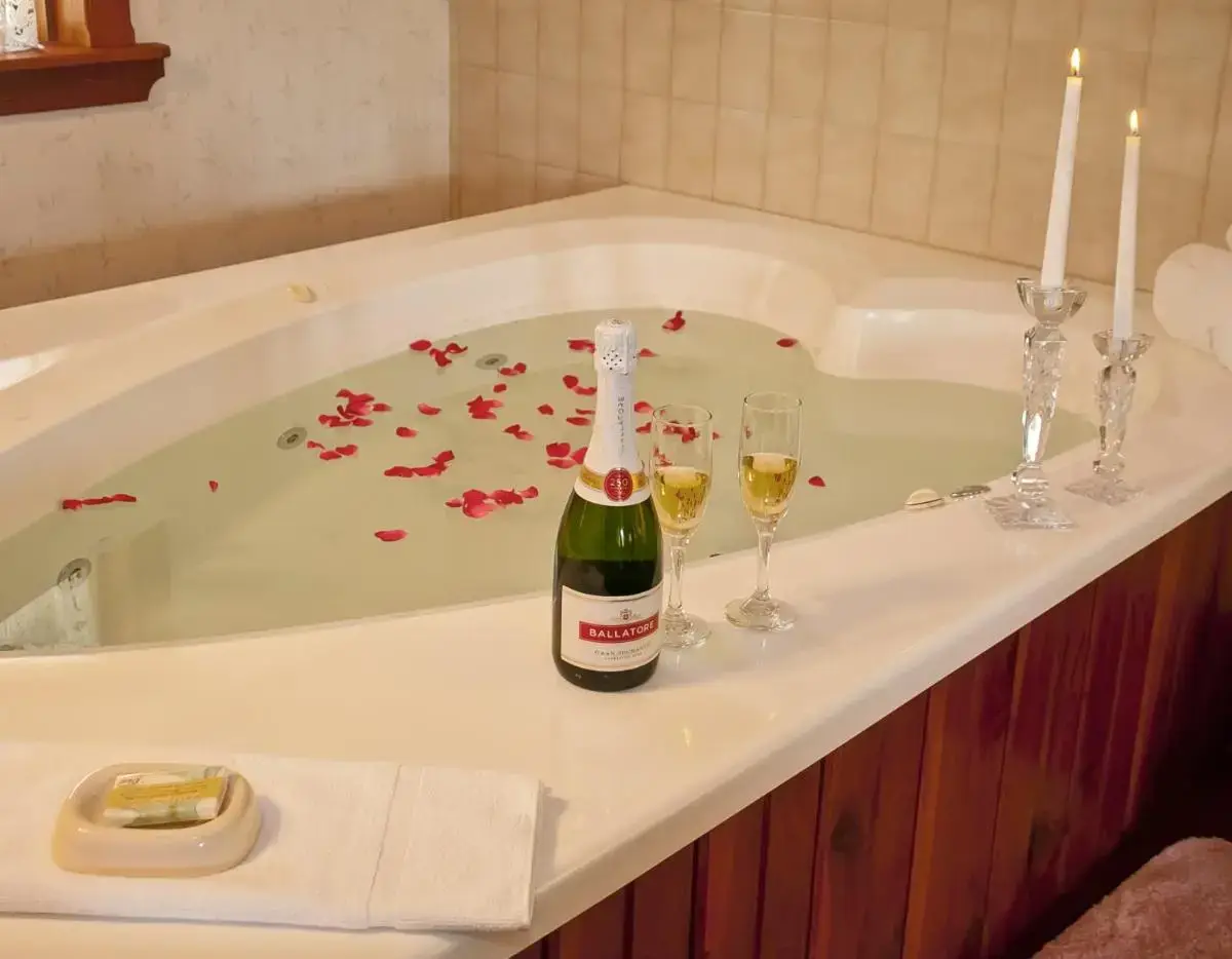 a bottle of champagne and two wine glasses in a bath tub at Bavarian Inn Motel in Eureka Springs