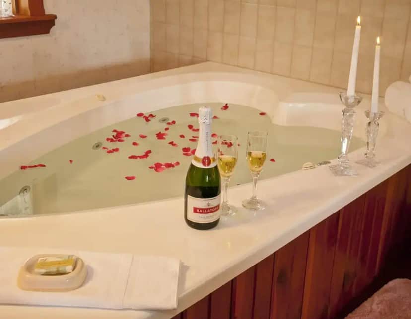 a bottle of champagne and two wine glasses in a bath tub at Bavarian Inn Motel in Eureka Springs