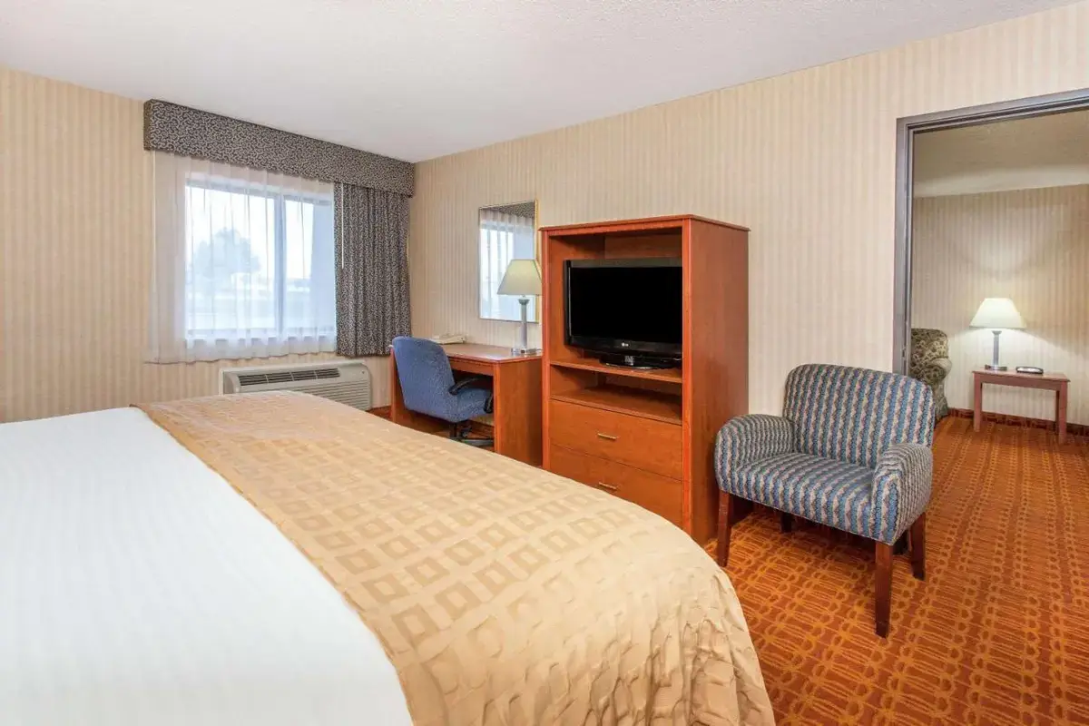 a hotel room with a bed and a television at Baymont by Wyndham Detroit/Roseville in Roseville