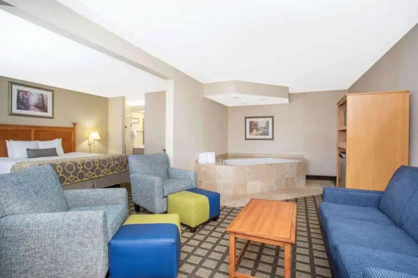 a hotel room with a bed and a tub at Baymont by Wyndham Hays in Hays