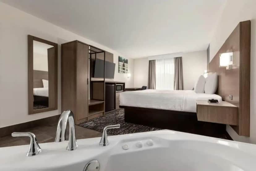 a hotel room with a bed and a bath tub at Baymont by Wyndham La Grange KY Southeast in La Grange