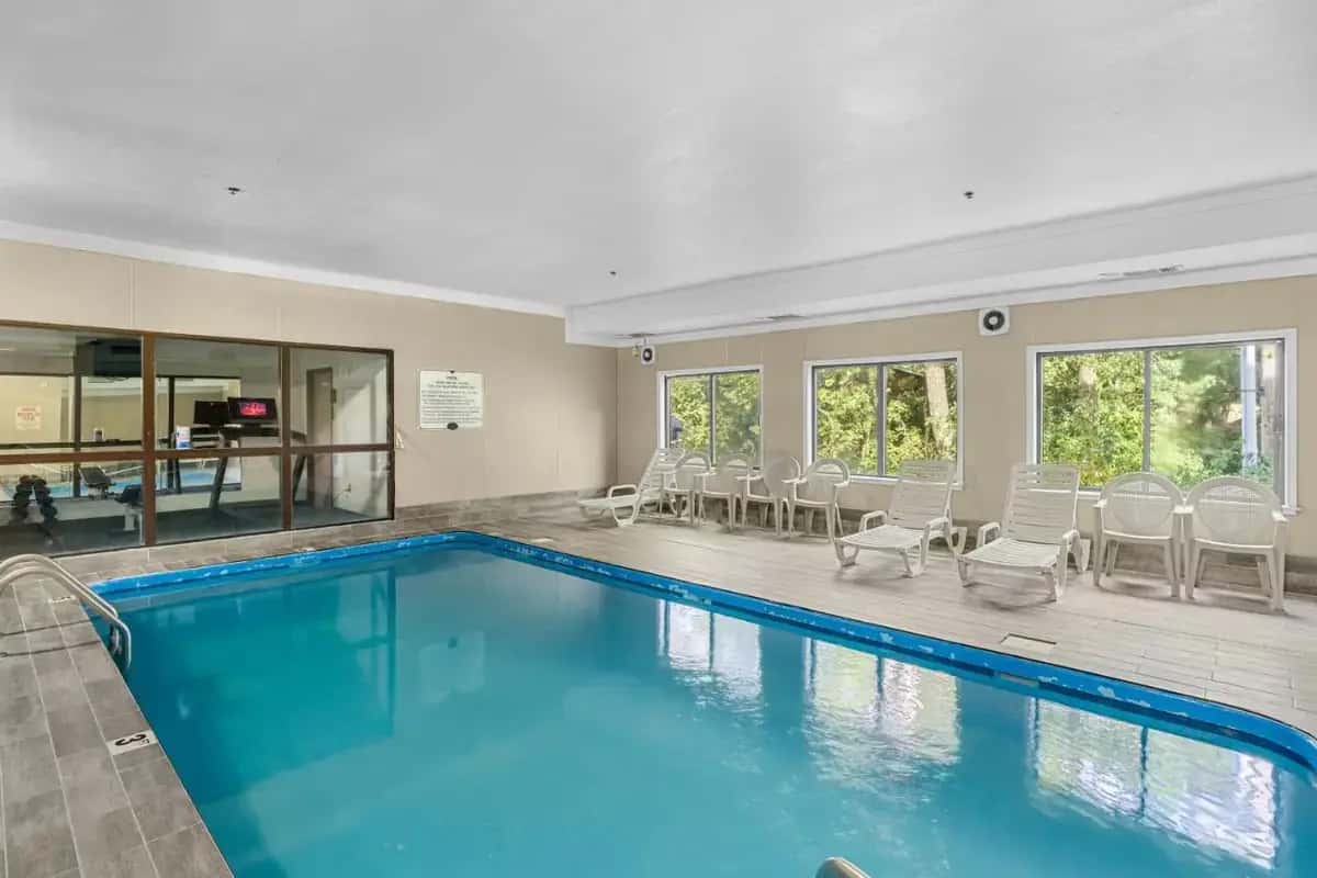 a swimming pool with chairs and a table at Baymont by Wyndham Lawrence in Lawrence