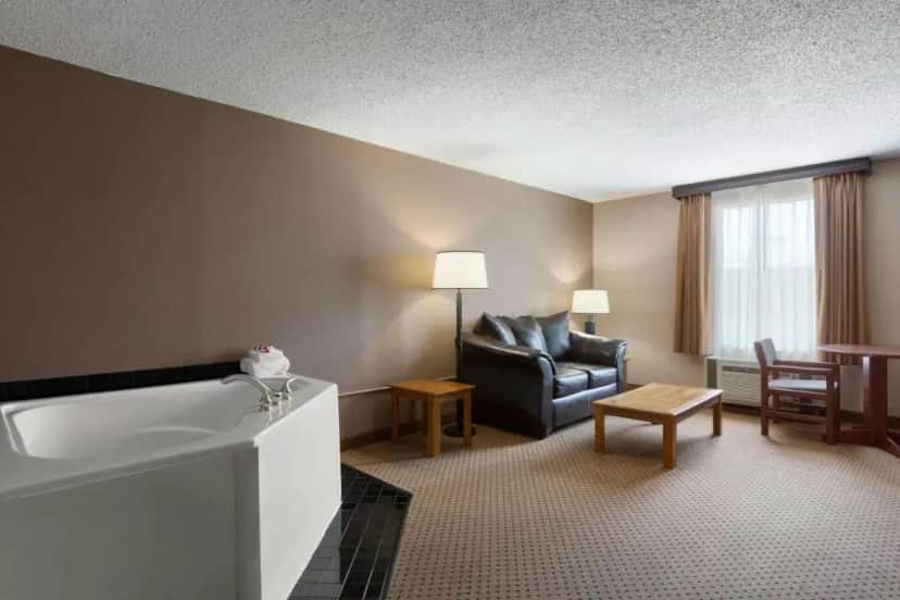 a hotel room with a bath tub and a couch at Baymont by Wyndham Mandan Bismarck Area in Mandan