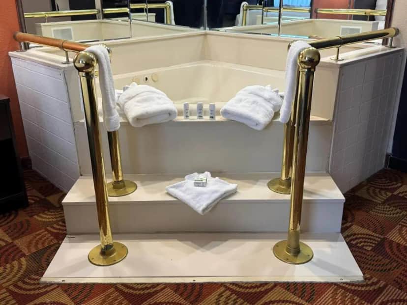 a bathroom with a tub with towels and a sink at Baymont by Wyndham Plainfield/ Indianapolis Arpt Area in Plainfield