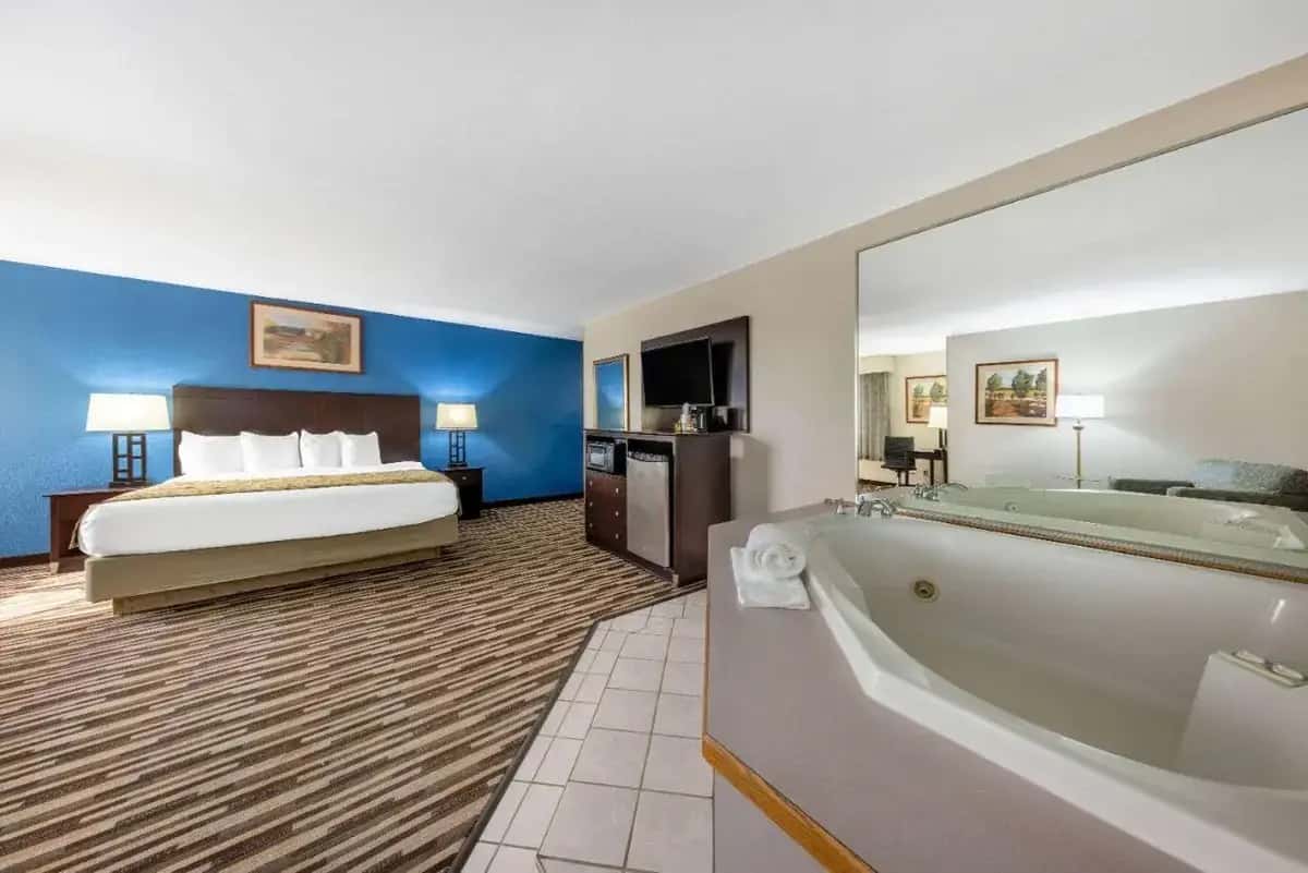 a hotel room with a bed and a bath tub at Baymont by Wyndham Springfield South Hwy 65 in Springfield
