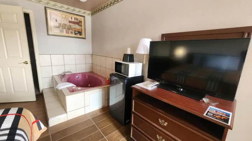 a bathroom with a television and a tub in a room at Benbrook Inn & Suites in Benbrook