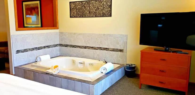a bath tub in a bedroom with a bed and a tv at Berlin Heritage Inn in Berlin