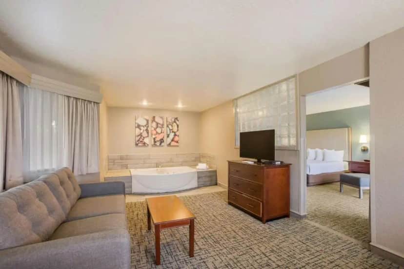 a hotel room with a couch and a bed and a television at Best Western Harbour Pointe Lakefront in Saint Ignace
