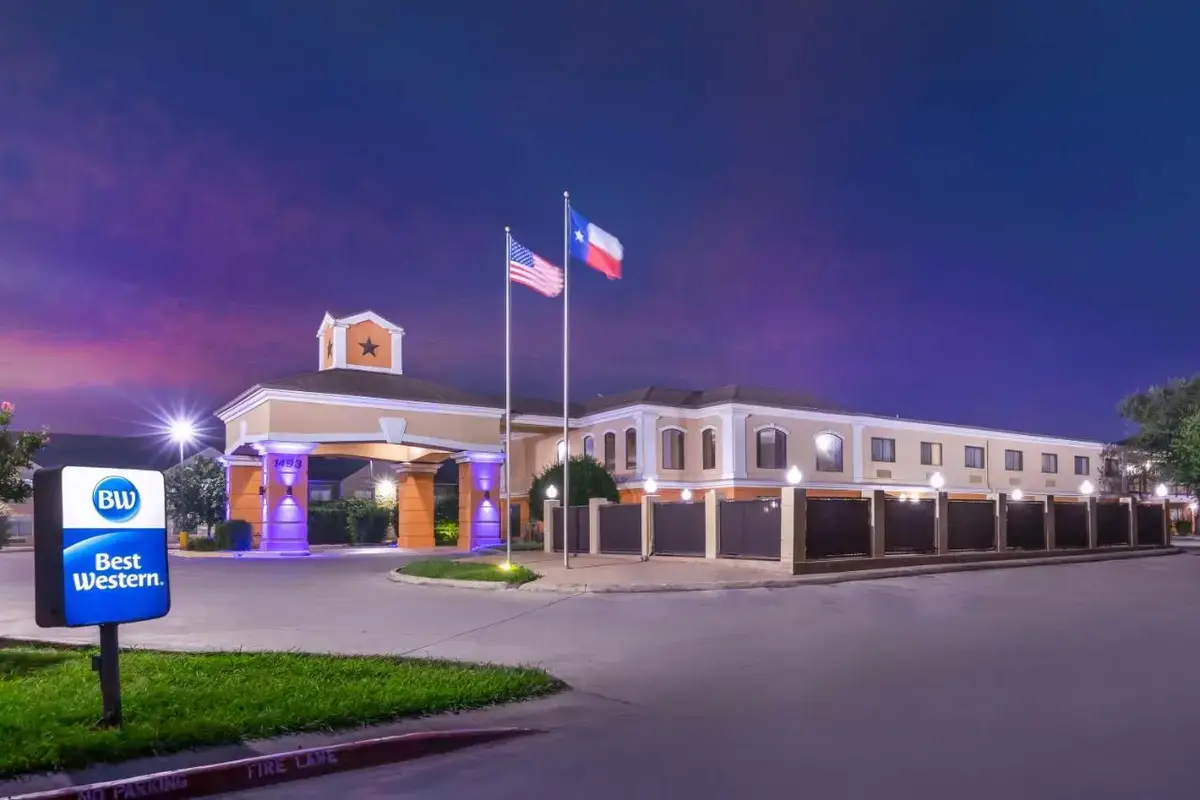 a building with two flags in front of it at night at Best Western Inn & Suites New Braunfels in New Braunfels