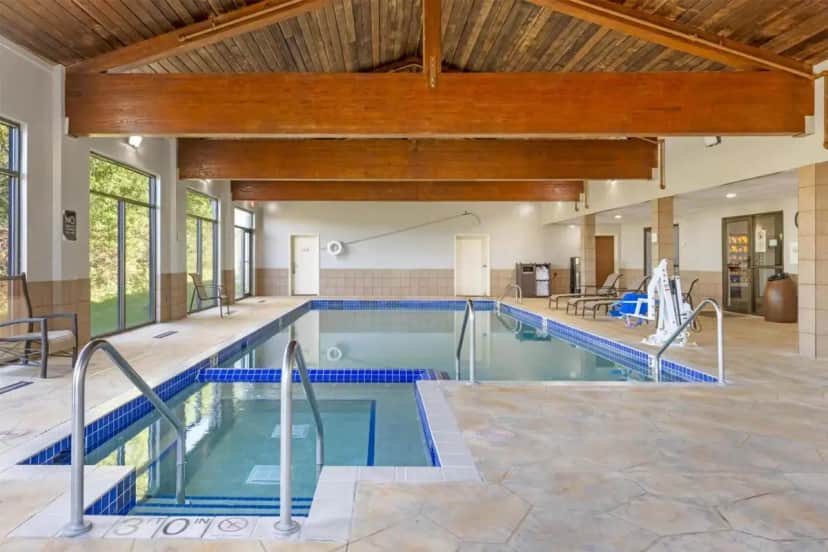 an indoor swimming pool with blue tile floors and a wooden ceiling at Best Western Plus Eau Claire Conference Center in Eau Claire
