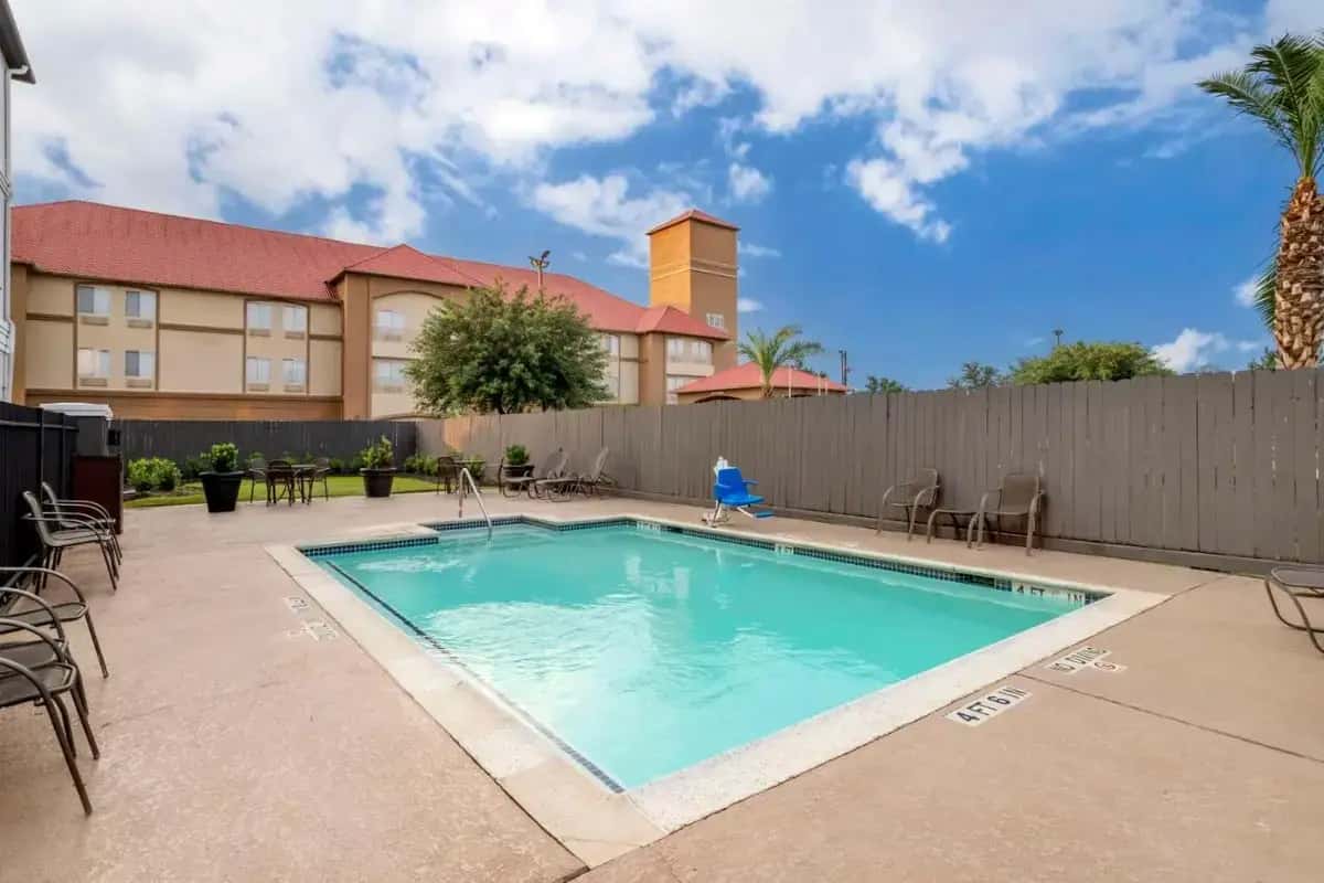 a swimming pool with chairs and a fence at Best Western Plus Hobby Airport Inn & Suites in Houston