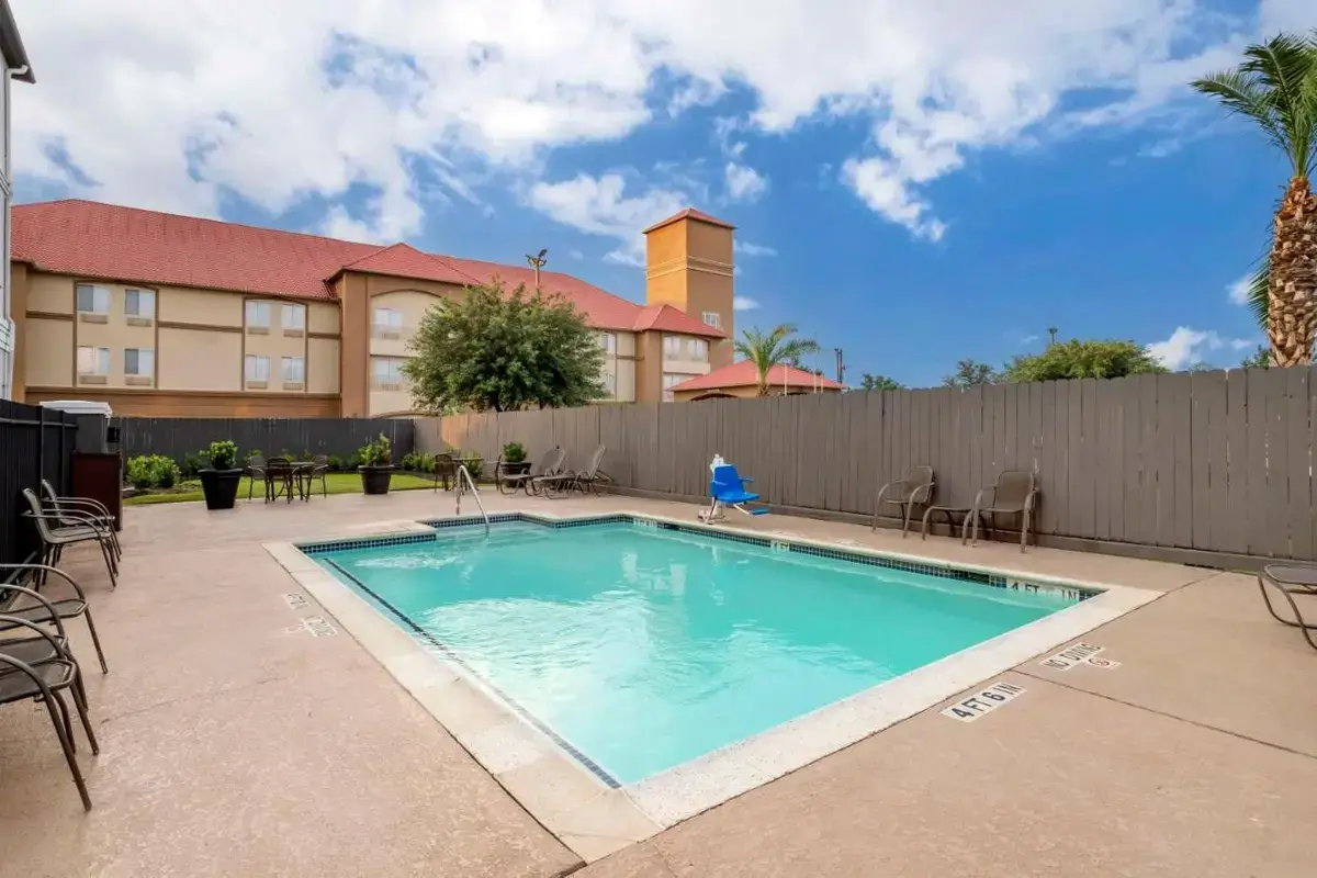 a swimming pool with chairs and a fence at Best Western Plus Hobby Airport Inn & Suites in Houston