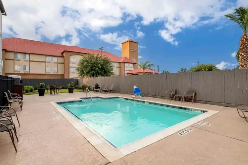 a swimming pool with chairs and a fence at Best Western Plus Hobby Airport Inn & Suites in Houston