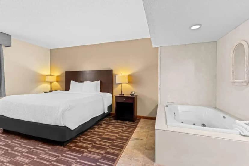 a hotel room with a bed and a bath tub at Best Western University Inn in Urbana