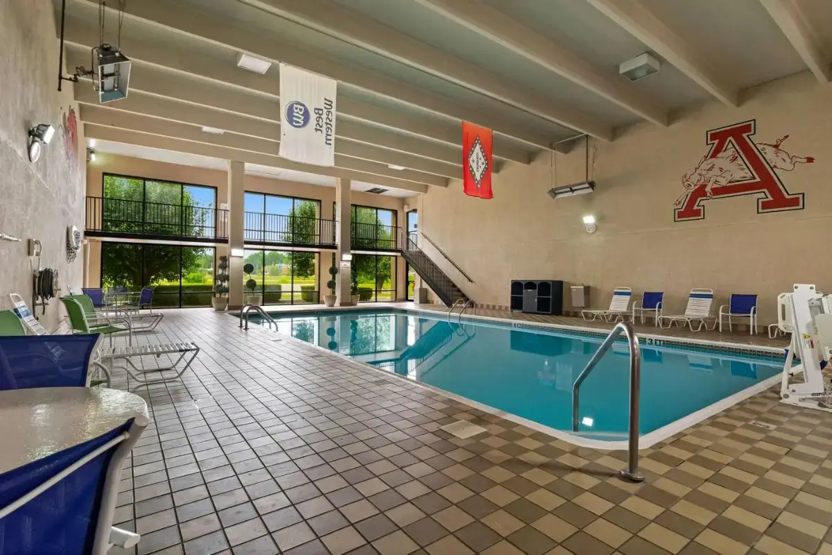 a pool in a hotel room with chairs and a table at Best Western Windsor Suites in Fayetteville