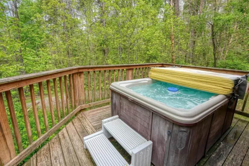 a hot tub on a deck with a bench at Blue Rose Cabins - Overlook Cabin in Logan
