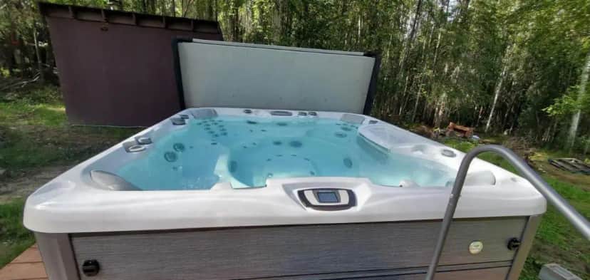 a jacuzzi tub in a backyard with a tree at Borealis Bungalow and Hot Tub in Fairbanks