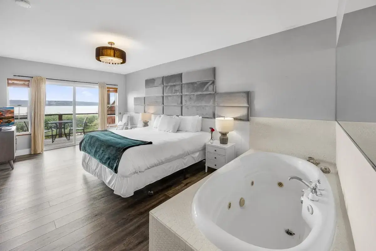 a bedroom with a bed and a bath tub next to a bathroom at Camano Island Inn in Camano