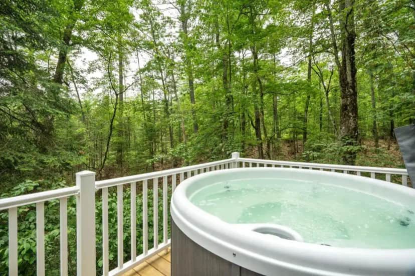 a hot tub on a deck with a view of the woods at Camp Conway Hot Tub AC New Kitchen Deck in Conway