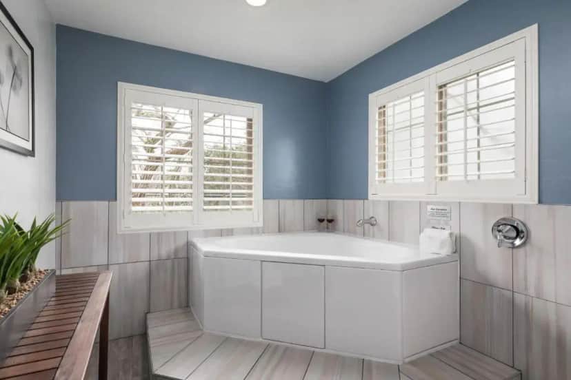 a bathroom with a white tub and two windows at Candle Light Inn in Carmel
