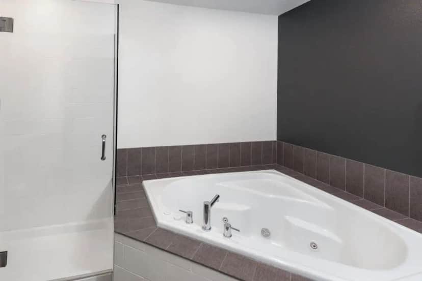 a bath tub in a bathroom with a tile wall at Caretta Landing Sarasota, an Ascend Collection Hotel in Sarasota