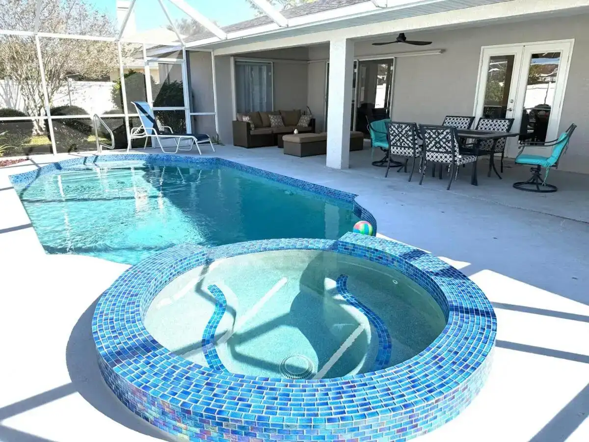 a swimming pool with blue tiles on a patio at Cheerful 5 bedroom home with heated pool in Sarasota