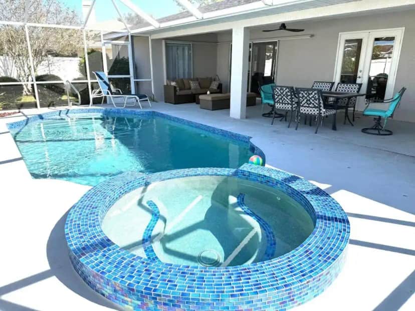 a swimming pool with blue tiles on a patio at Cheerful 5 bedroom home with heated pool in Sarasota