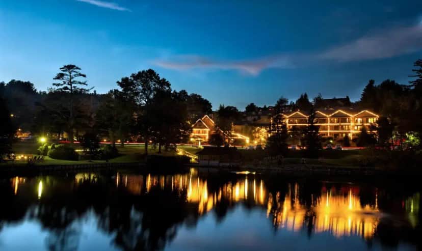 a view of a house with a lake at night at Chetola Resort in Blowing Rock