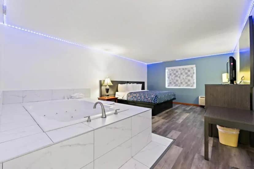 a bathroom with a tub and a bedroom with a bed at Chicago Club Inn & Suite in Oakbrook Terrace