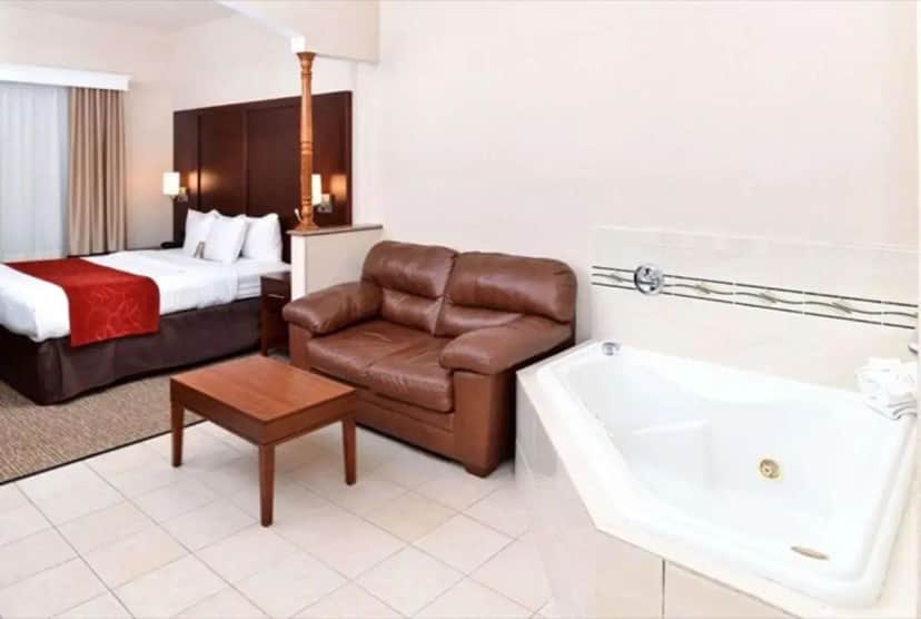 a hotel room with a couch and a bed and a tub at Citrus Suites Redlands Loma Linda Hotel in Redlands