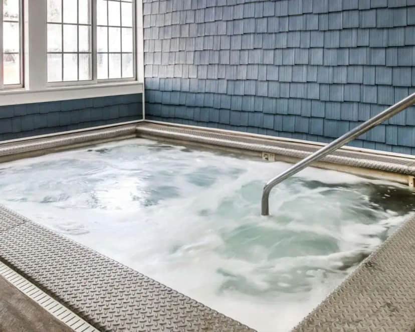 a jacuzzi tub in a blue tiled room at Clarion Hotel Mackinaw City Beachfront in Mackinaw City