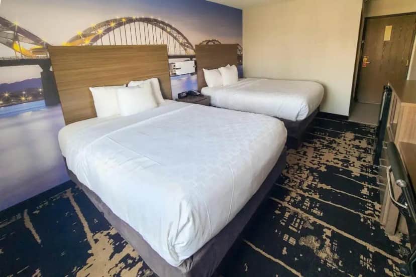 a hotel room with two beds with white sheets at Clarion Pointe Bettendorf - Quad Cities in Bettendorf