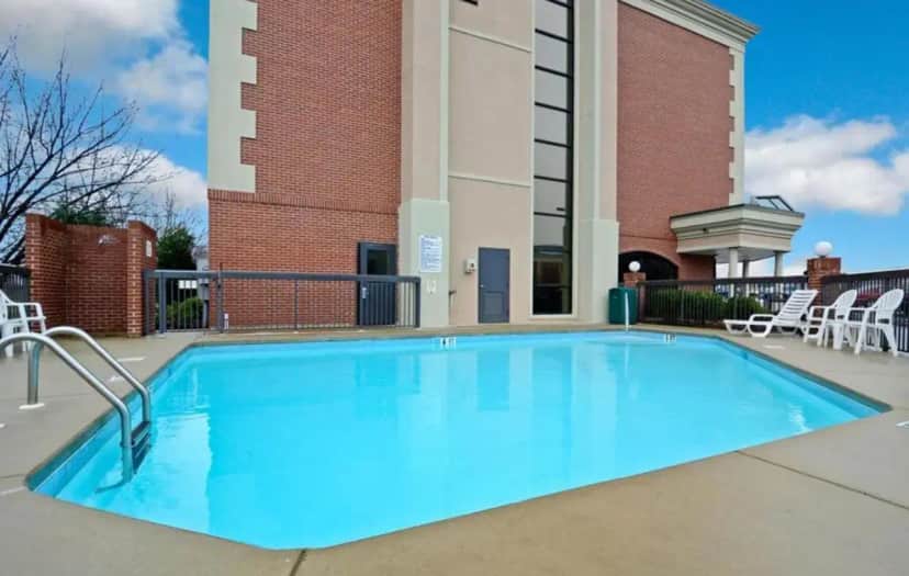 a swimming pool in front of a building at Clarion Pointe Greensboro Airport in Greensboro