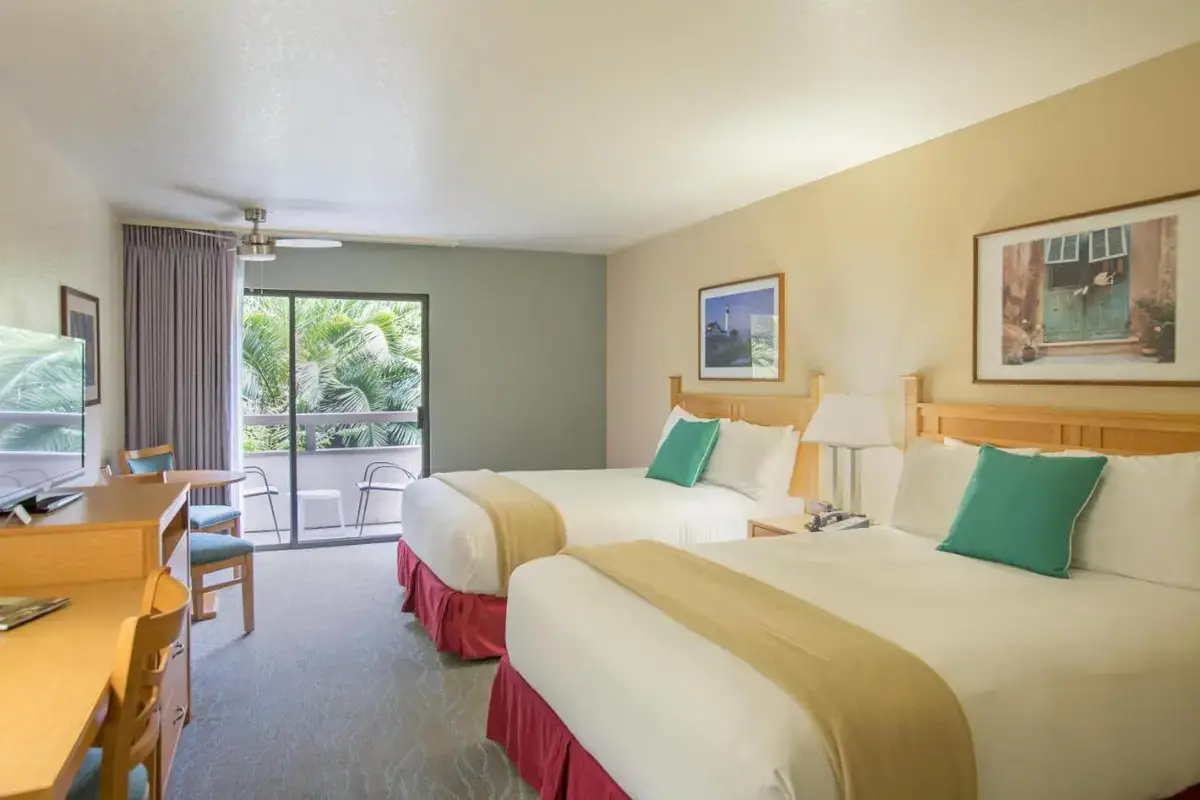 a hotel room with two beds and a desk at Colton Inn in Monterey