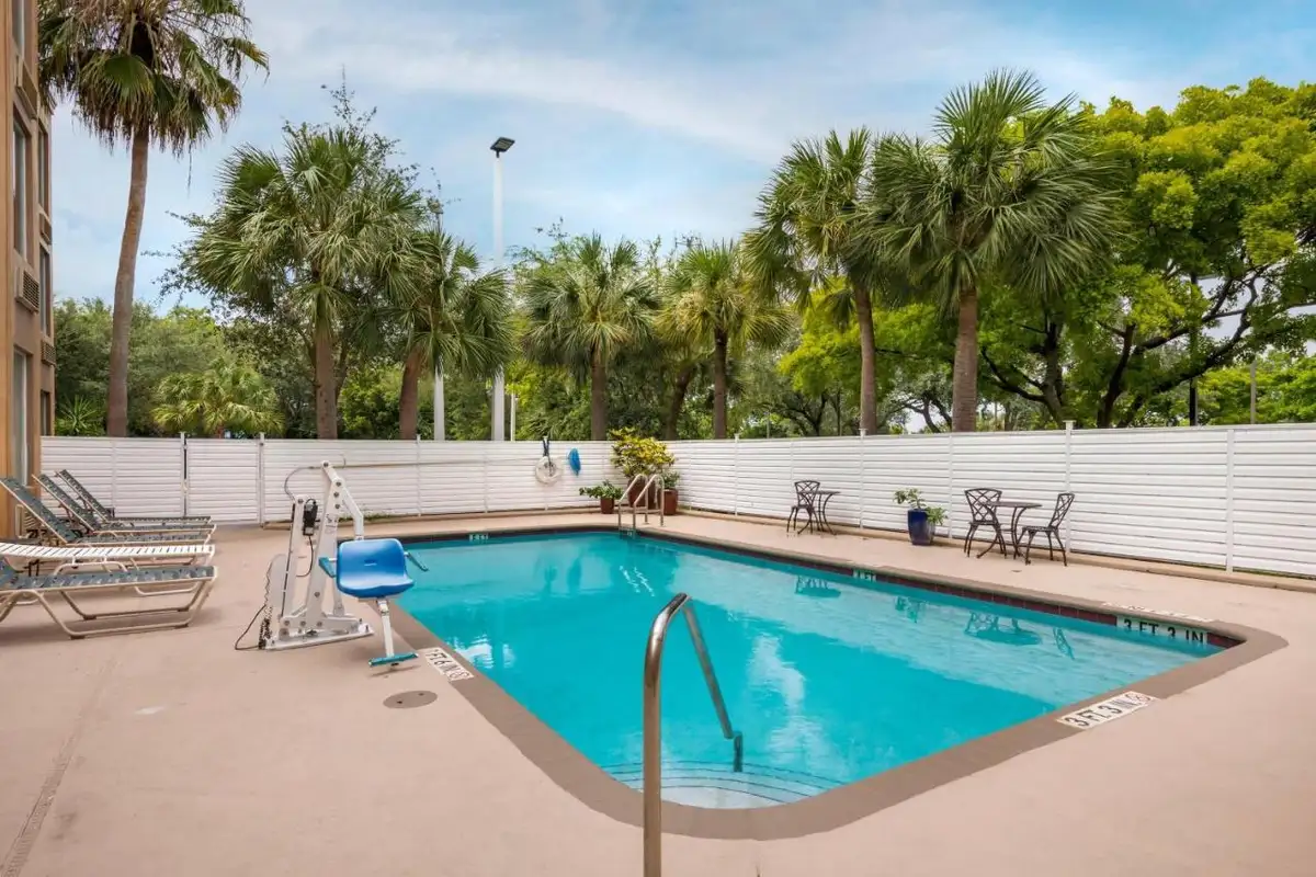 a swimming pool with chairs and trees in the background at Comfort Inn & Suites Fort Lauderdale West Turnpike in Fort Lauderdale