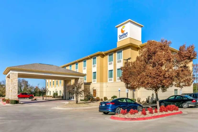 a hotel with cars parked in front of a building at Comfort Inn & Suites Van Buren - Fort Smith in Van Buren